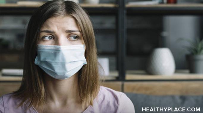 A woman with brown hair has a surgical mask on